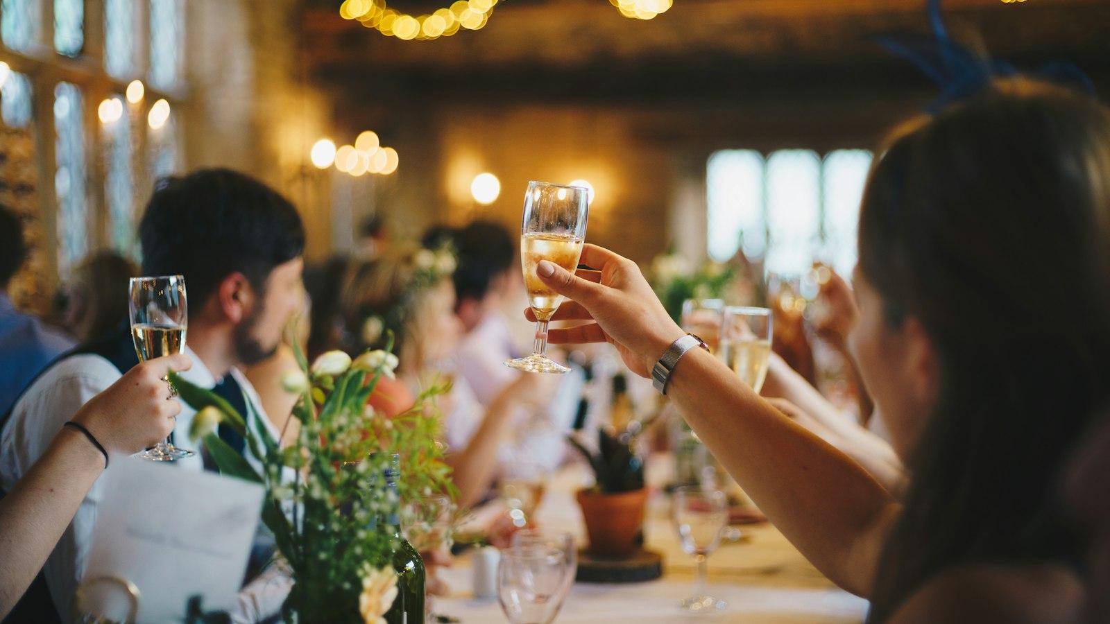 Raised glasses at a long table under warm string lights