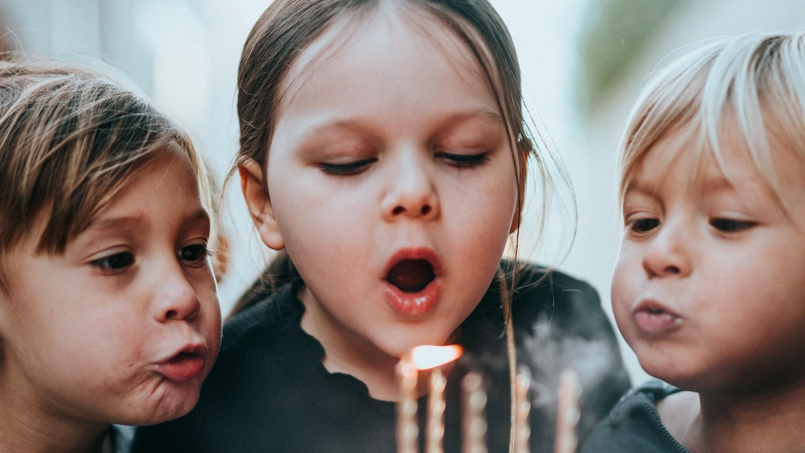 Children blowing out the candles on a birthday cake together