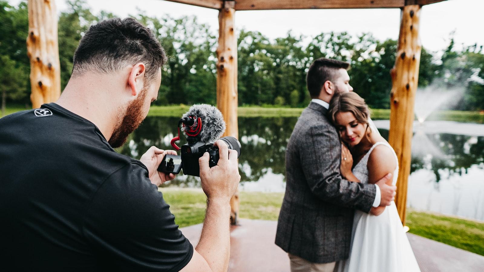 A wedding photographer photographing a couple beside a lake