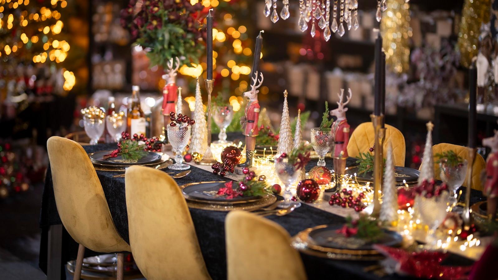 A festive holiday party table set with candles, greenery and gold chairs