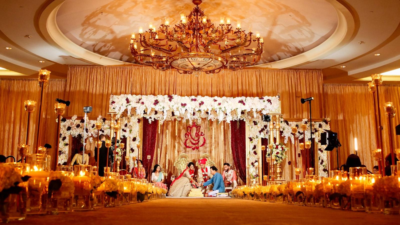 A couple in traditional wedding attire during a ceremony beneath a floral canopy