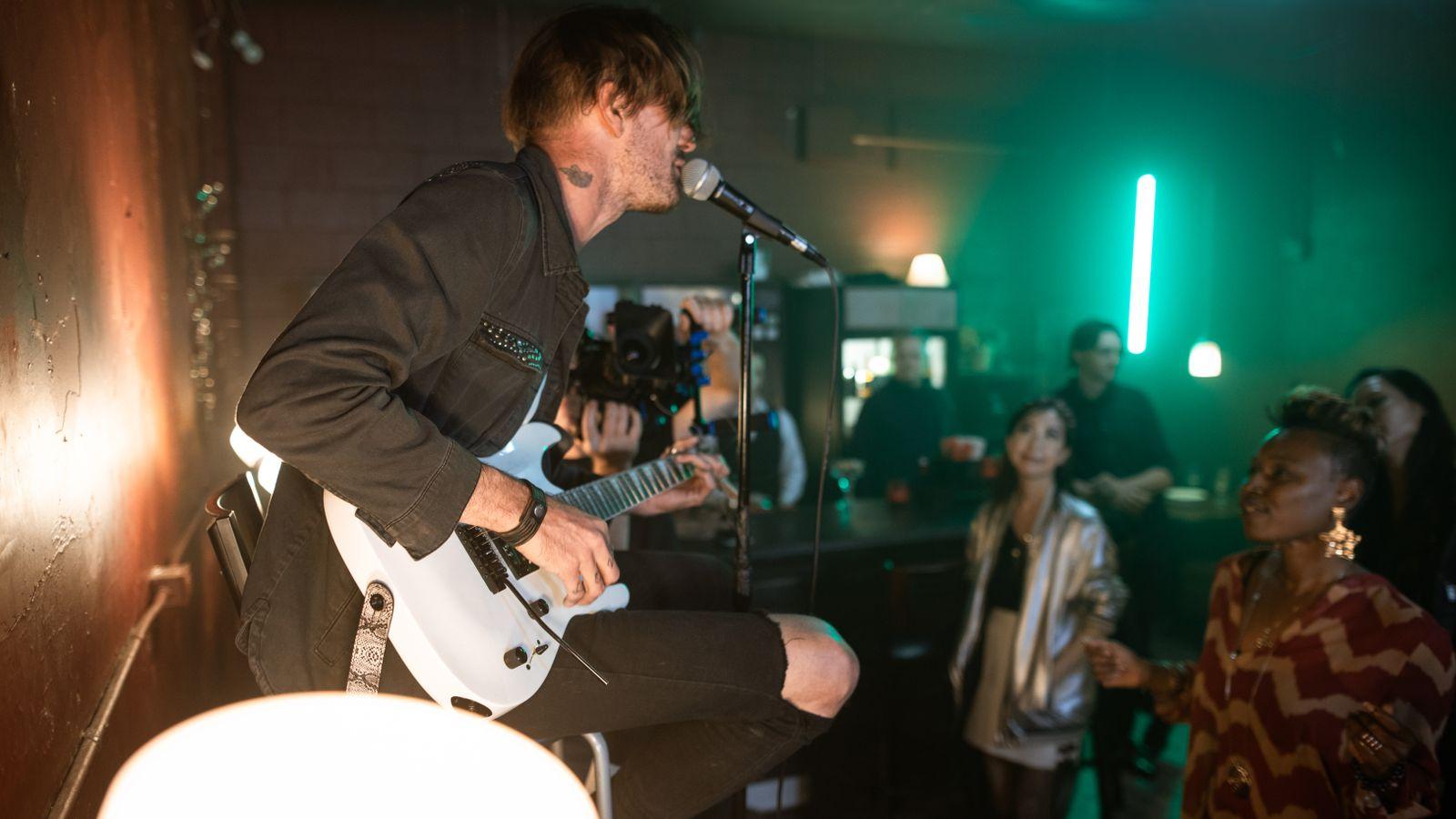 A singer playing guitar on a small stage with the crowd close by