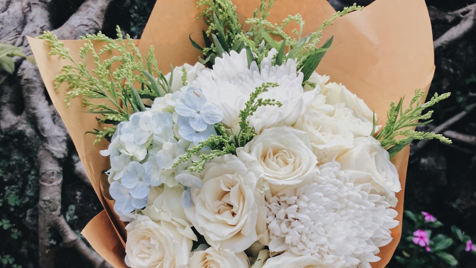 A florist holding a freshly wrapped bouquet of white and cream blooms