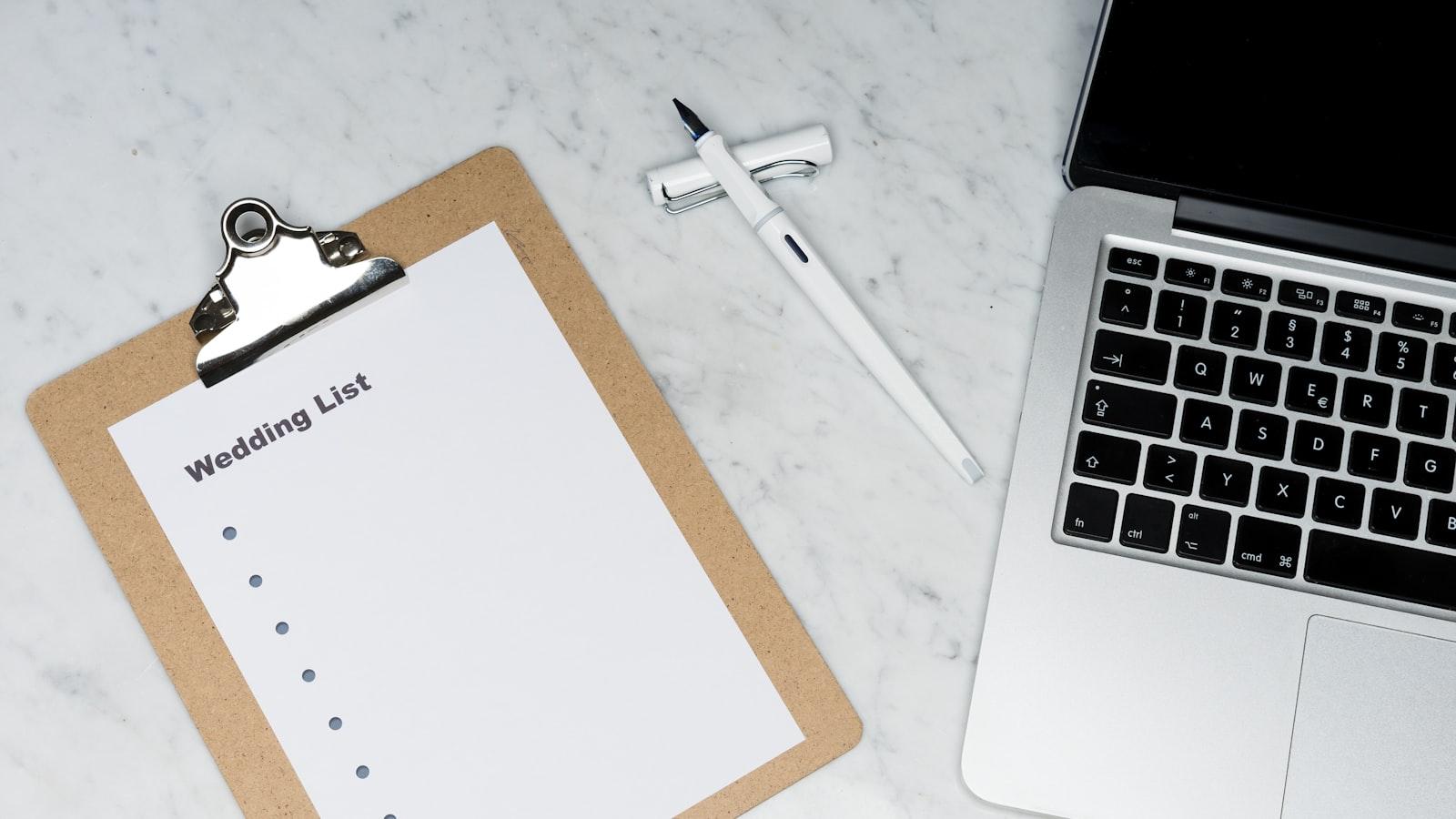 A wedding checklist on a clipboard beside a laptop