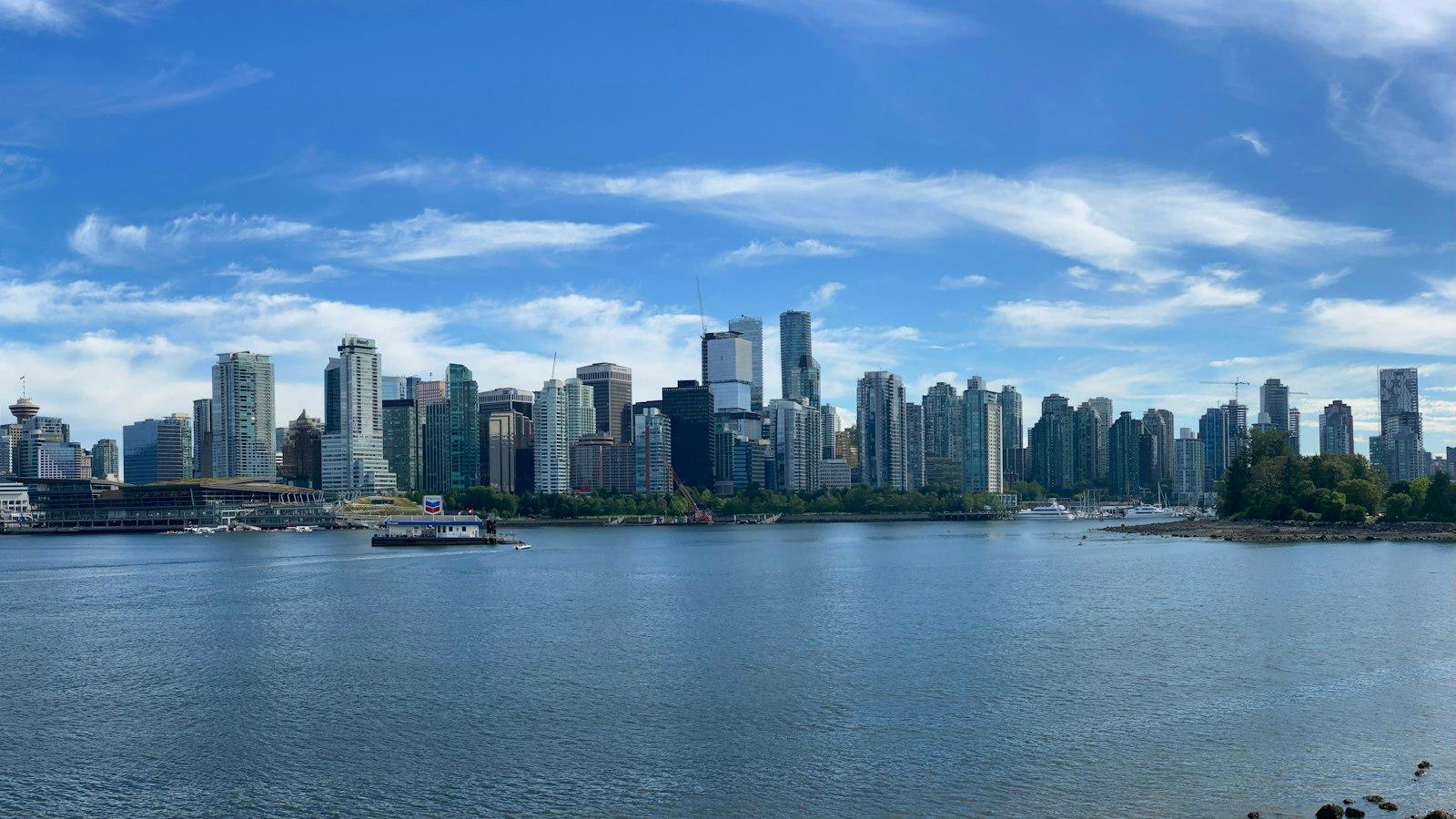 The Vancouver skyline and harbour seen from Stanley Park, with a small boat on the water